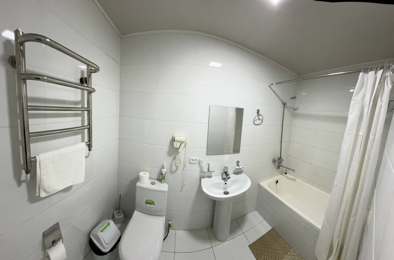 Ein modernes Badezimmer mit integriertem Waschbecken, einem Schminkspiegel, einem Handtuchhalter, einer Toilette und einer Duschkabine.