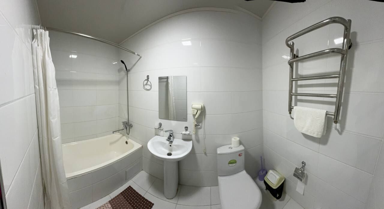 A modern bathroom with a bathtub, sink, toilet, and a towel rack.