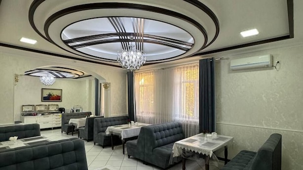 Een moderne hotel lobby met een centrale zithoek, een kroonluchter en een eethoek.