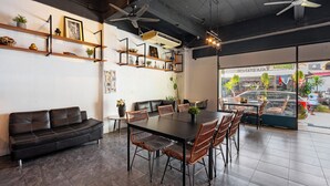 A modern interior with a black leather sofa, a dining table with wicker chairs, and a ceiling fan. - Kata Station (Karon)