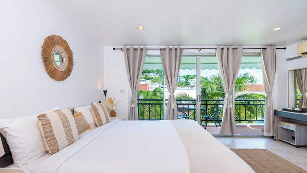 A spacious bedroom with a large bed, a balcony with a view, and a modern bathroom. - Kata Station (Karon)