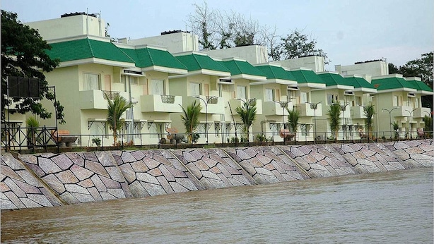 A row of modern, multi-story buildings with green roofs and balconies, adjacent to a body of water.