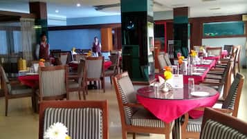 Un restaurante con mesas redondas, sillas a rayas y manteles rojos.