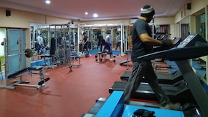 A gym with treadmills, weight machines, and a mirrored wall.