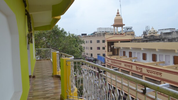 A balcony with a view of a temple and surrounding buildings. - Hotel Samman (Varanasi)