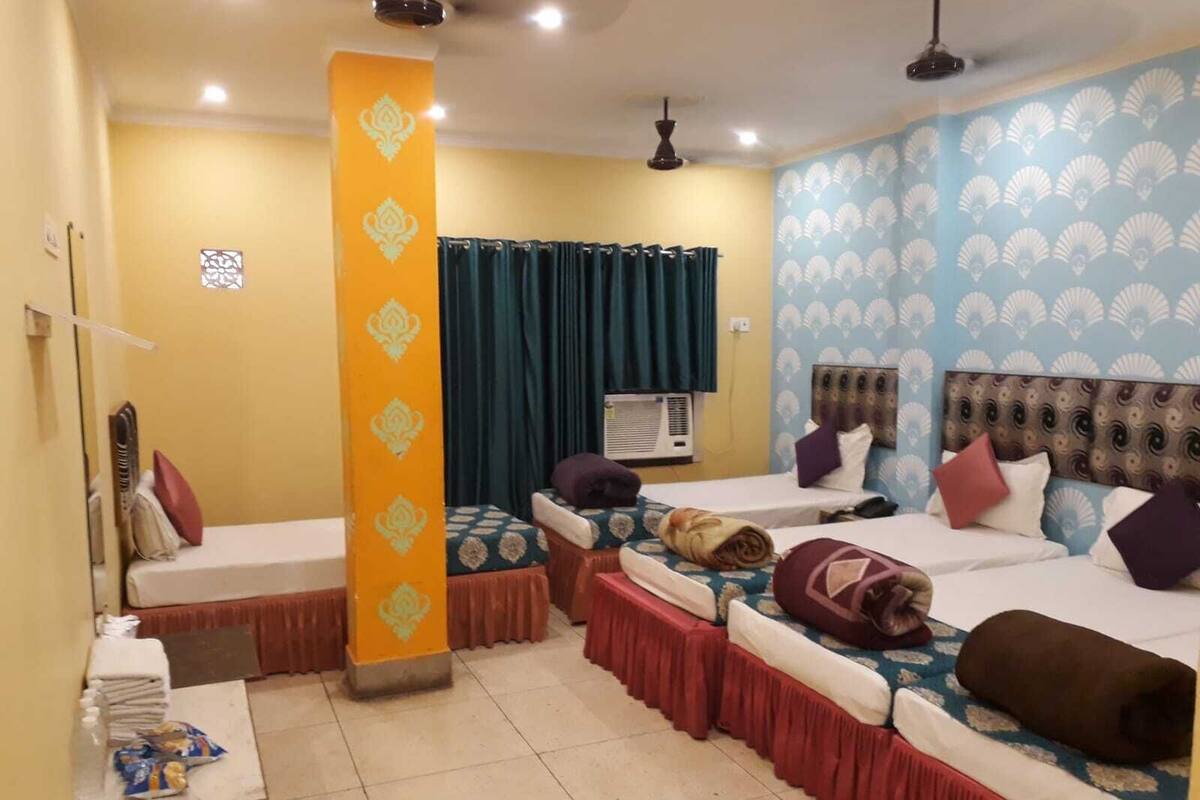 A hotel room with two beds, a small table with snacks, an air conditioning unit, and a decorative pillar.
