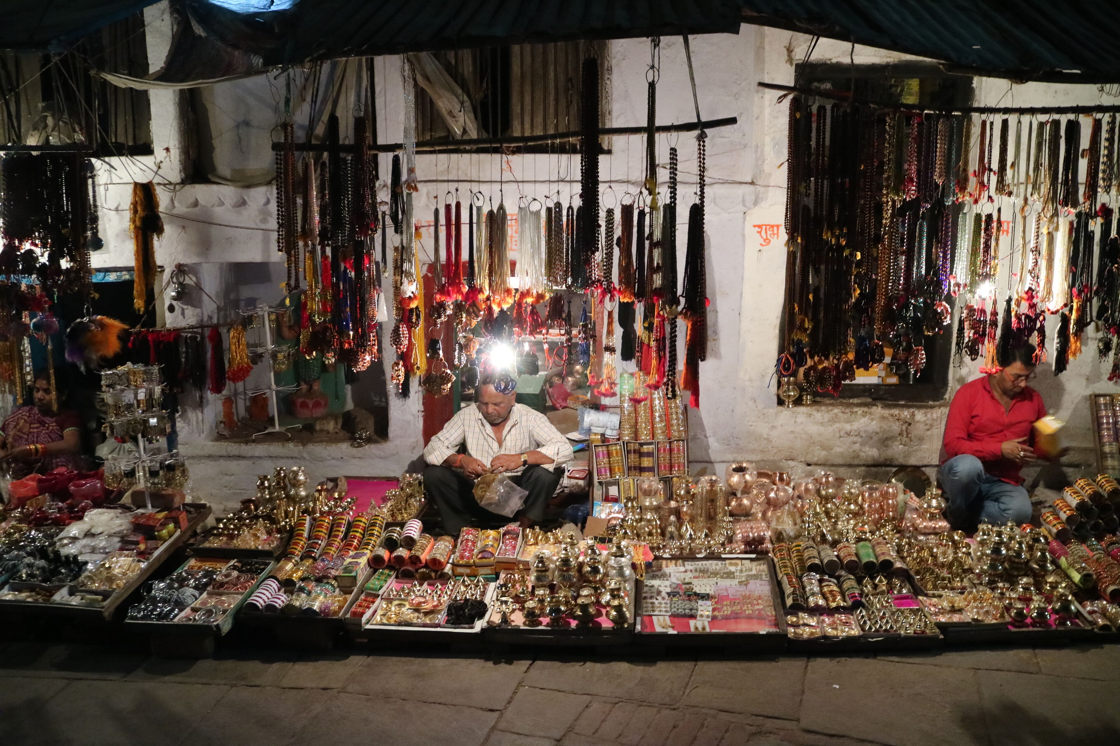 A market stall with various jewelry items and a person sitting in the foreground.