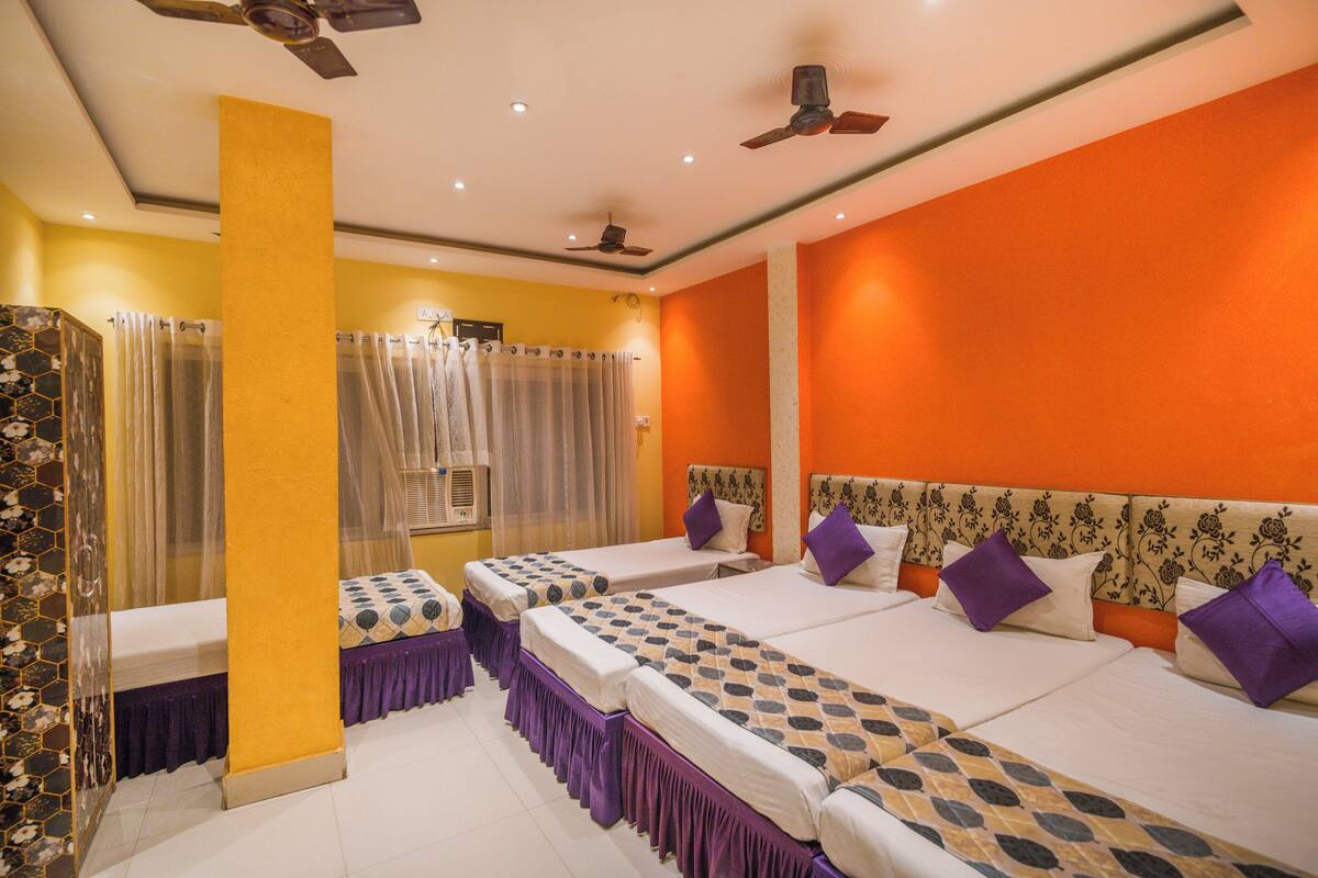 A hotel room with three beds, a shower area, and a ceiling fan.