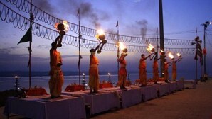 Monks performing a ritual with flaming torches in a coastal setting. - Hotel Samman (Varanasi)