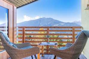 A wooden deck with wicker chairs and a table, overlooking a mountain range. - Haus Lasaun (Bressanone)