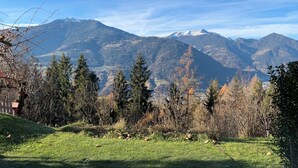 A view from a covered outdoor area with a wooden roof, overlooking a mountainous landscape with snow-capped peaks and a valley below. - Haus Lasaun (Bressanone)