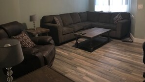 A living room with a sectional sofa, a coffee table, and a lamp. - Royal Retreat 3 Downtown South Charleston  (South Charleston)