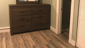 A room with a wooden dresser, a mirror, and a door leading to another room. - Royal Retreat 3 Downtown South Charleston  (South Charleston)