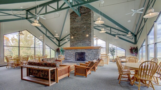A spacious room with a stone fireplace, wooden furniture, and large windows. - Lively condo-central location! Ready your great adventures for every season! (Silverthorne)