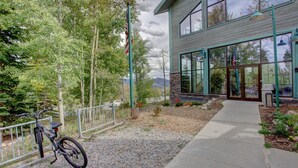 A building with a stone facade, large windows, and a gravel pathway leading to a metal fence. - Lively condo-central location! Ready your great adventures for every season! (Silverthorne)