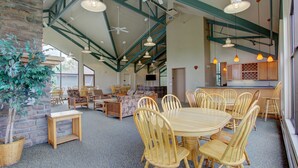 A spacious room with a high ceiling, wooden chairs around a central table, and a kitchen area with wooden cabinets. - Lively condo-central location! Ready your great adventures for every season! (Silverthorne)