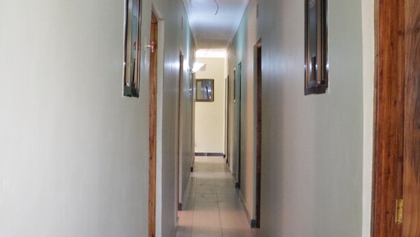 A hallway with doors on both sides, a light fixture on the left, and a door on the right.