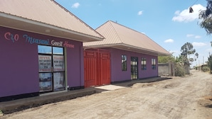 A guest house with a purple exterior, a red door, and a signboard advertising a hot shower, breakfast, and TV.