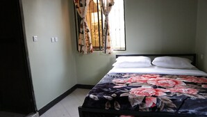 A bedroom with a bed, a window with curtains, and a door.