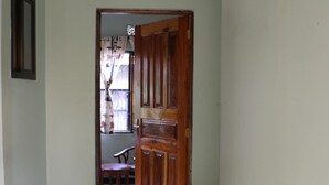 A hallway with a wooden door, a chair, and a window with a curtain.