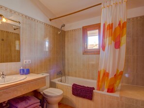 Ein Badezimmer mit Badewanne, Toilette, Waschbecken und einem Fenster.