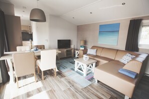 Una sala de estar moderna con sofá, sillas, televisor y comedor.