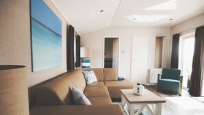 A modern living room with a brown sofa, a coffee table, a lamp, and a view of the outdoors.