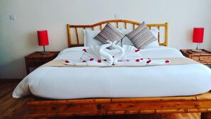 A neatly made bed with a wooden headboard, white bedding, and a swan-shaped towel arrangement. - Peaks Hotel Limited (Nanyuki)