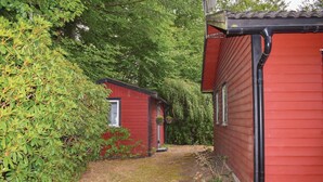 Un sendero estrecho que lleva a un edificio rojo con una ventana pequeña y una puerta.