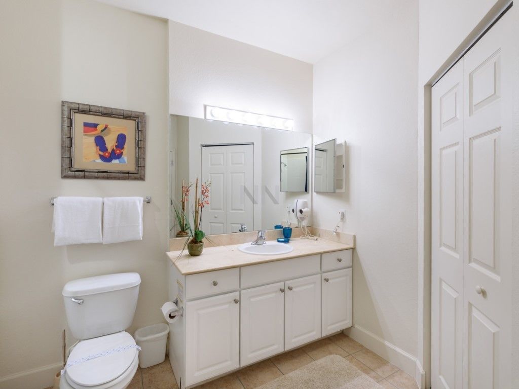 A bathroom with a toilet, sink, and cabinets.