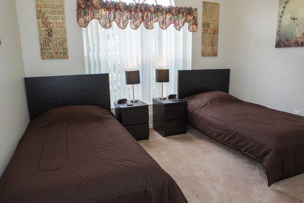 Un dormitorio con dos camas individuales, un espejo, mesitas de noche y una cortina decorativa.