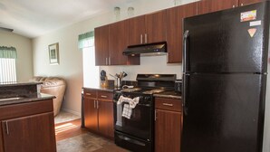 A compact kitchen with dark wooden cabinets, a black refrigerator, and a stove. - Ip60433 - Wellington - 4 Bed 2 Baths Villa (Davenport)