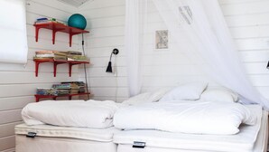 Ein Schlafzimmer mit einem Bett, einem Regal mit Büchern und einem Ball sowie einer Wandlampe.