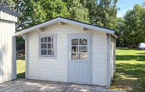 A small, single-story shed with a gabled roof and two windows, one with a door. - Awesome home in Löttorp with sauna (Löttorp)