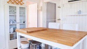 Eine Küche mit Holztisch, weißen Schränken und einer hängenden Stange.