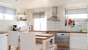 Eine moderne Küche mit weißen Schränken, einer Holzauskładung, einem Edelstahl-Geschirrspüler und einem Fenster mit Streifenjalousien.