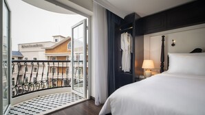 A hotel room with a large bed, a nightstand with a lamp, a view of the outside balcony, and a checkered floor mat. - My Boutique Hotel & Spa (Sa Pa)