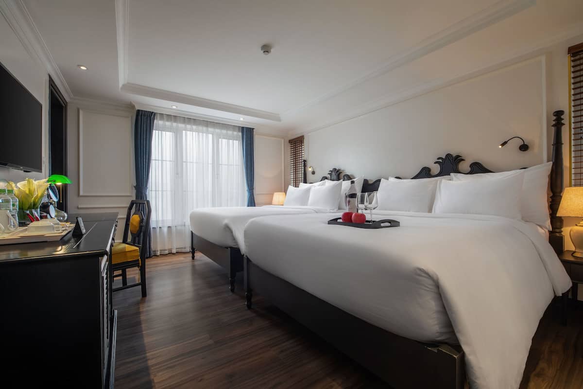 Habitació d'hotel amb un llit gran, un escriptori amb cadira, una televisió de pantalla plana i una finestra amb cortines.