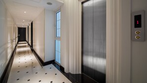 A modern hallway with a polished floor, a large elevator, and a digital display showing the number 1. - My Boutique Hotel & Spa (Sa Pa)