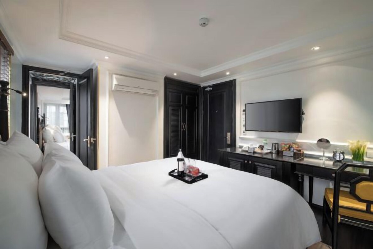 Ein Hotelzimmer mit einem großen Bett, einem Schreibtisch und einem Flachbildfernseher, gestaltet im modernen Stil.