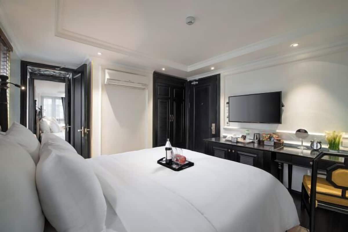 Une chambre d’hôtel dotée d’un grand lit, d’un bureau avec un téléviseur à écran plat et d’un design moderne.