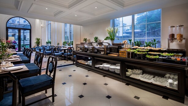 A hotel dining area with a buffet, seating arrangements, and large windows. - My Boutique Hotel & Spa (Sa Pa)