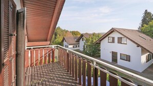A wooden balcony with a view of white houses and a clear sky.