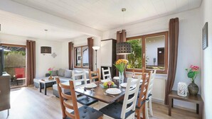 A dining area with a wooden table, white chairs, and a vase of flowers.