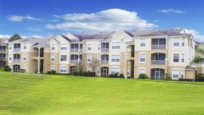 A multi-story residential building with a symmetrical facade, balconies, and a well-maintained lawn in front. - Ip60127 - Windsor Palms Resort - 3 Bed 2 Baths Condo (Kissimmee)