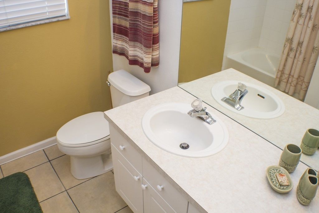 A bathroom with a toilet, a sink with a mirror, and a bathtub.