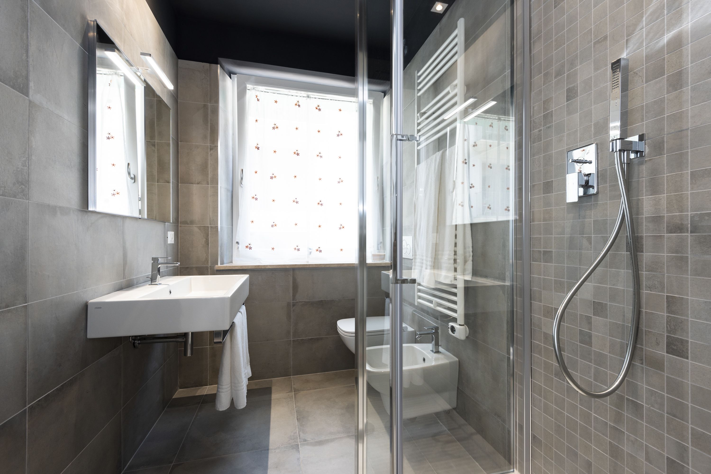 A modern bathroom with a glass-enclosed shower, a white sink, and a toilet.