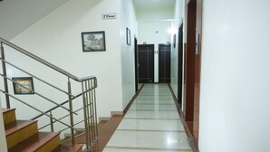 A hallway with a staircase leading to the second floor, a sign indicating the floor level, and a door at the end. - Balaji Lodging (Pandharpur)
