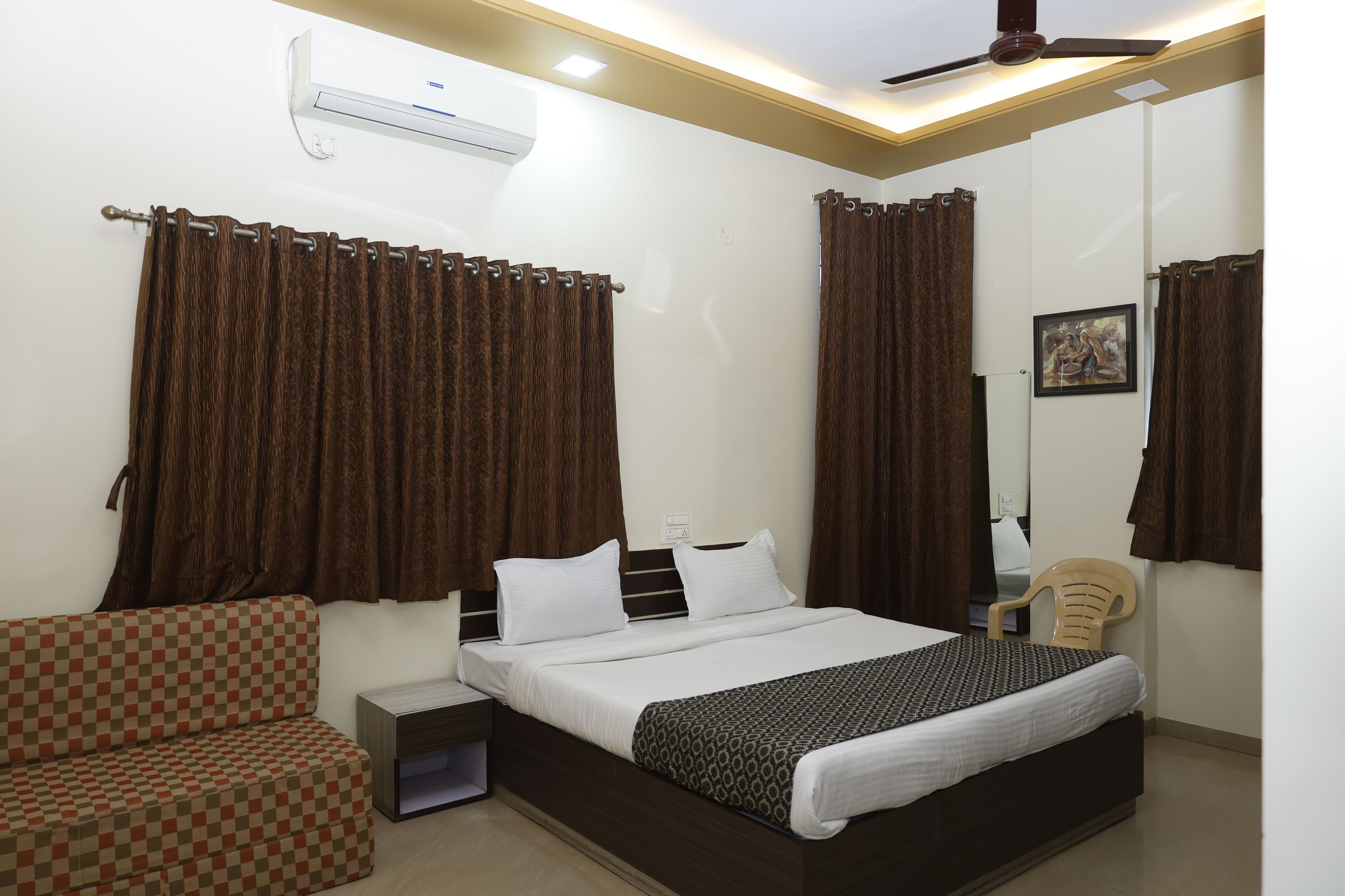A bedroom with a bed, a chair, a bedside table, and curtains.