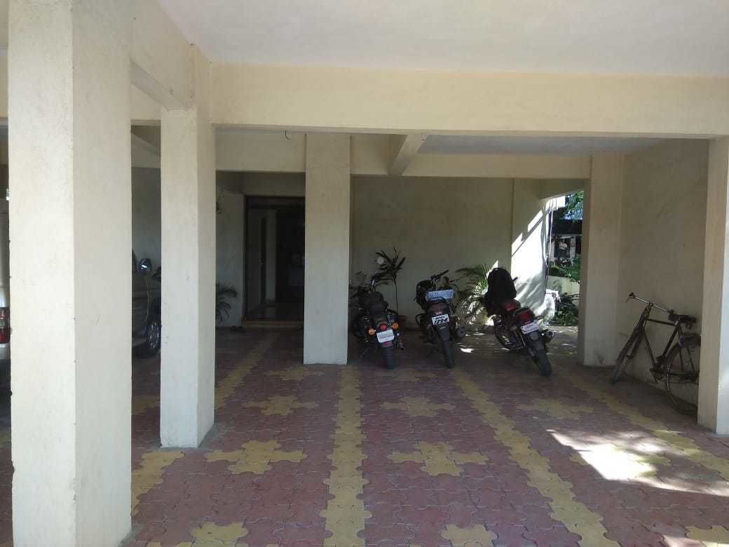 A covered parking area with tiled flooring and several parked motorcycles.